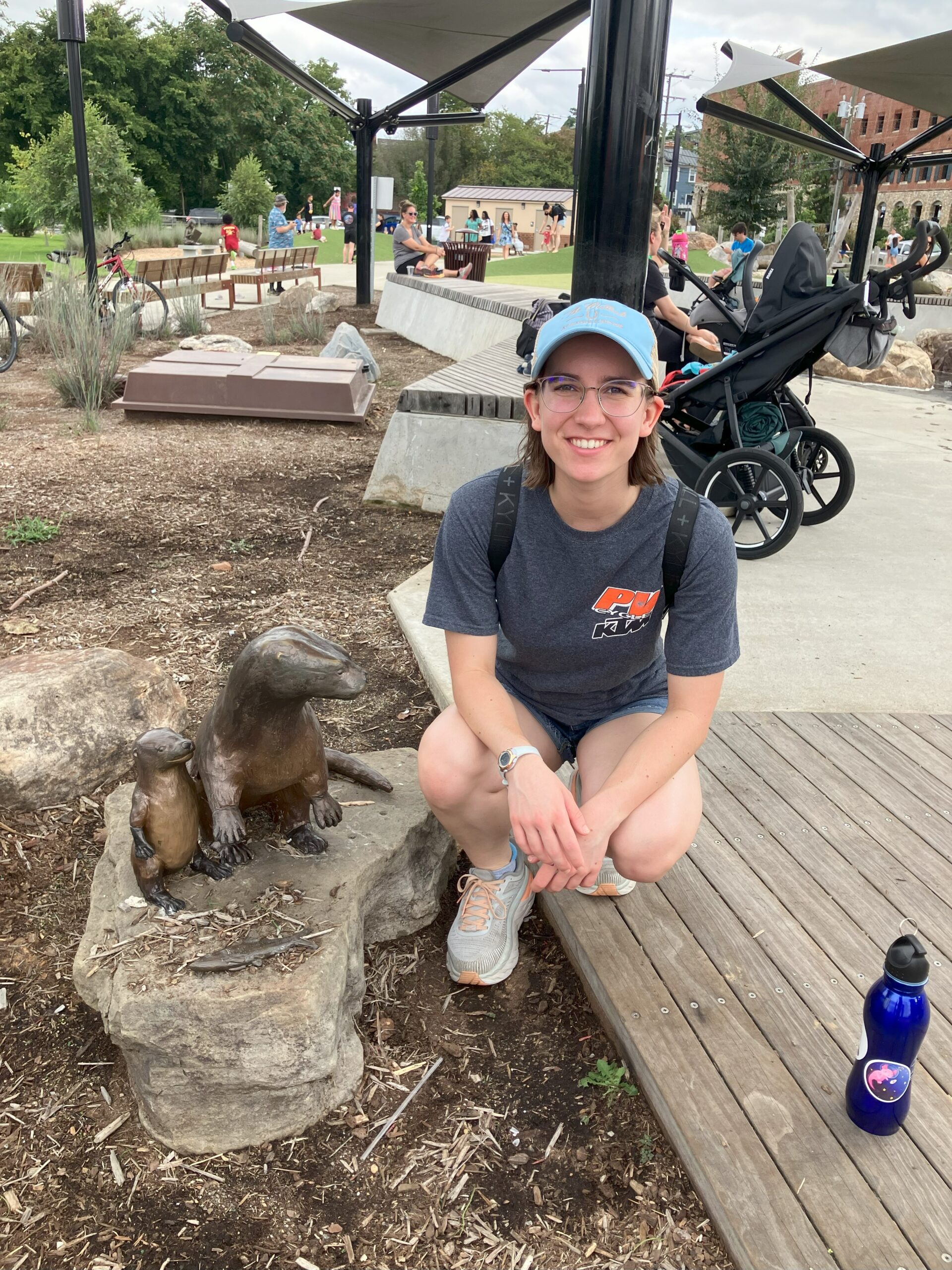 Woman squatting next to a statue of an otter